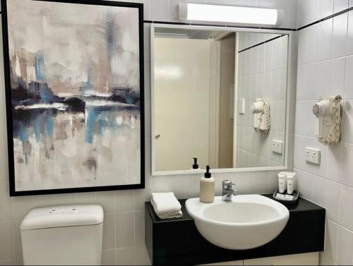 ein Badezimmer mit einem Waschbecken, einem Spiegel und einem WC in der Unterkunft Prime Location 1 Bdr Apt in Perth in Perth