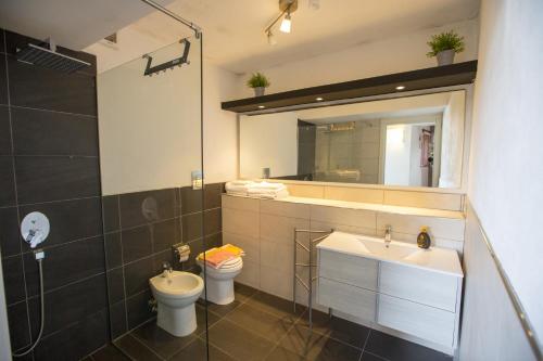 een badkamer met een wastafel, een toilet en een spiegel bij Mulino in Cefalù