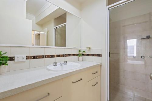 biała łazienka z umywalką i prysznicem w obiekcie East Perth Apartment with Free Wi-Fi and Parking w mieście Perth