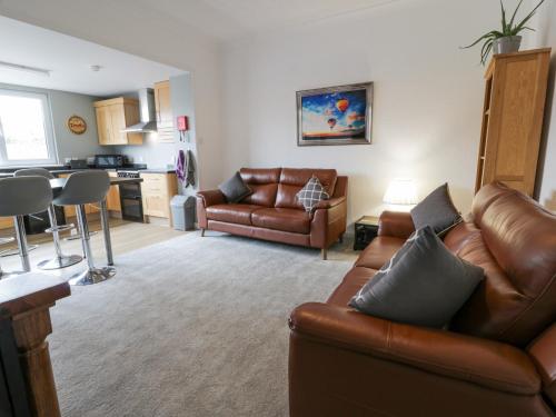 a living room with a leather couch and a kitchen at Little Ireland in Stranraer