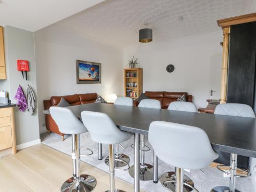 a dining room with a black table and white chairs at Little Ireland in Stranraer
