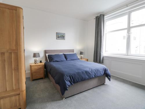 - une chambre avec un lit doté de draps bleus et une fenêtre dans l'établissement Little Ireland, à Stranraer
