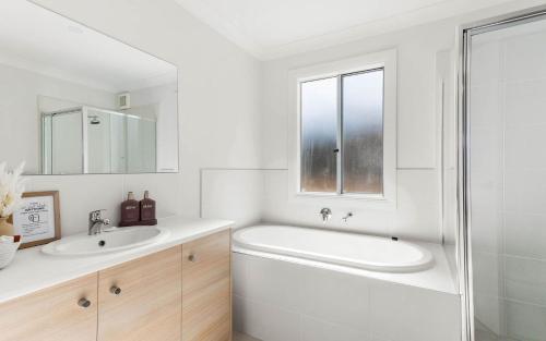 a white bathroom with a tub and a sink at Beyond Beach House in Goolwa South