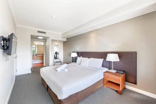 a bedroom with a large white bed and a television at Idyllic Waterfront Pool Escape with Esplanade View in Darwin