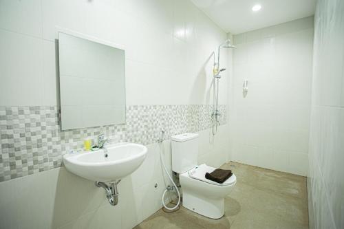 Baño blanco con lavabo y aseo en De Luna Guest House, en Kuripan