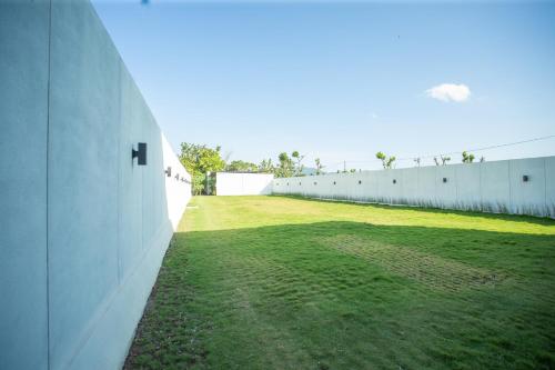 a large field of grass next to a white wall at De Luna Guest House in Kuripan