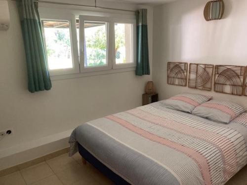 Un dormitorio con una cama y dos ventanas. en Un jardin dans la ville, en La Ciotat