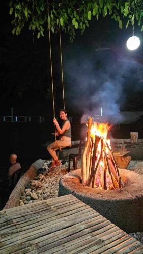 a man sitting on a bench next to a fire at Eagles Nest Beach Resort in Davao City