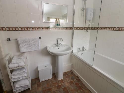 a white bathroom with a sink and a tub and a mirror at Oak Cottage in Appleby