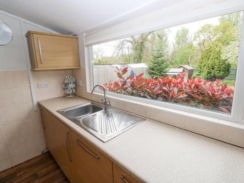 a kitchen with a sink and a large window at Ewenny Cottage in Bridgend