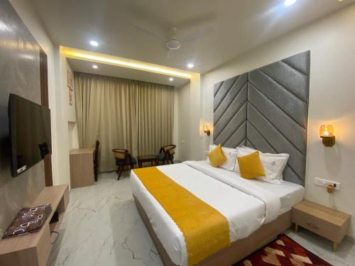 une chambre d'hôtel avec un lit et une télévision dans l'établissement Hotel Aditya Grand, à Bhopal