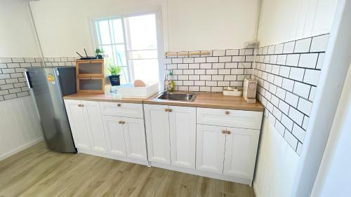 a kitchen with white cabinets and a stainless steel refrigerator at บ้านไร่ฟ้าสวยวังน้ำเขียว Nordic 01 in Ban Kom