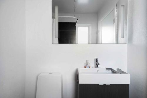 a white bathroom with a sink and a mirror at Holiday Apartment At Beautiful Solgaarden 6 in Svaneke