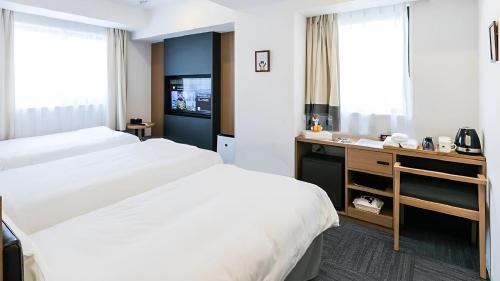 a hotel room with two beds and a desk at Henn na Hotel Osaka Namba in Osaka