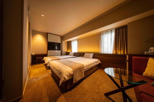 a hotel room with two beds and a glass table at New Osaka Hotel in Osaka