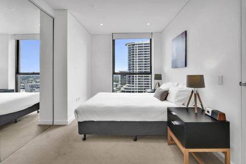 1 Schlafzimmer mit 2 Betten, einem Schreibtisch und Fenstern in der Unterkunft Amazing two bedroom St Leonards ATC62010 in Sydney