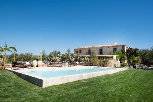 una piscina en un patio con una casa al fondo en Baglio Siciliamo Country House, en Marina di Noto