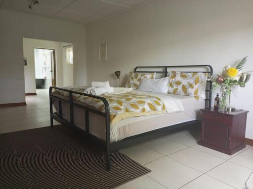 een slaapkamer met een bed en een tafel met bloemen erop bij Spacious 3 bedroom house in Lilayi, Lusaka in Lusaka