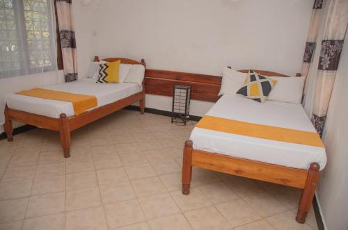 1 dormitorio con 2 camas y ventana en KANAMAI PRIME VILLAS, en Mombasa