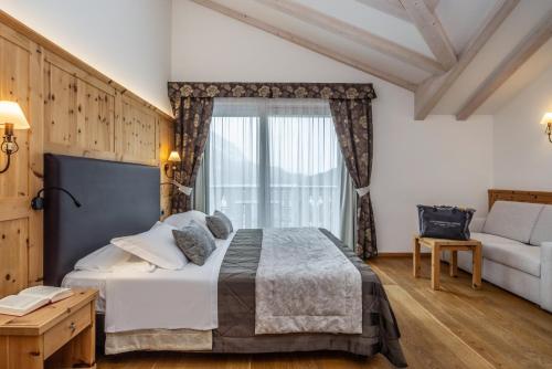 a bedroom with a bed and a couch and a window at Alpenresort Belvedere in Molveno