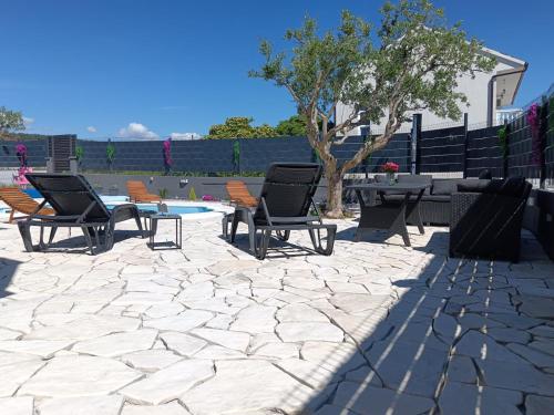 a patio with chairs and a table and a table and a tree at Apartments Feliks in Ljubač