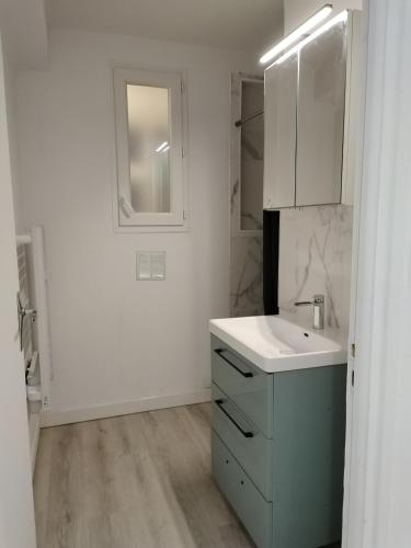 une salle de bain blanche avec un lavabo et un miroir dans l'établissement Appartement entier, à Montpellier