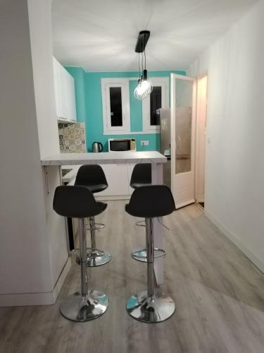 une cuisine avec trois tabourets de bar devant un comptoir dans l'établissement Appartement entier, à Montpellier