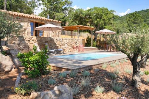 une piscine avec des parasols et une maison dans l'établissement La Bergerie des Oliviers, à Conca