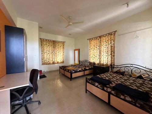 Habitación con 2 camas, escritorio y ordenador. en Tapovan Villa & Resort, en Pune