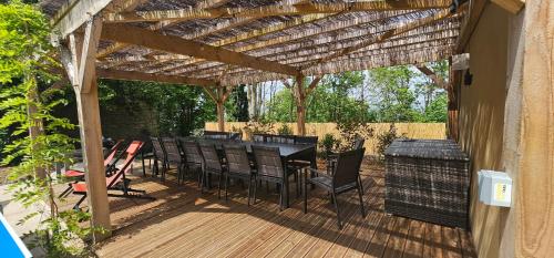 a wooden deck with a table and chairs under a wooden pergola at Le Clos Maldier - Gîte de la Belle vue in Laon