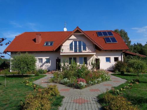 een huis met een rood dak en een tuin bij Gospodarstwo Agroturystyczne Leśna Polanka in Gietrzwałd