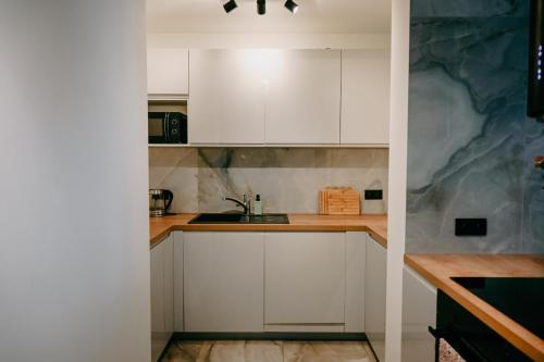 a kitchen with white cabinets and a counter top at Apartment by the River II in Szczecin