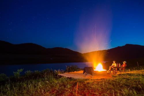een groep mensen die 's nachts rond een kampvuur zitten bij Etm Lodge 