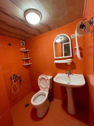 baño de color naranja con aseo y lavamanos en Emilis Vacation Home, en Kobuleti