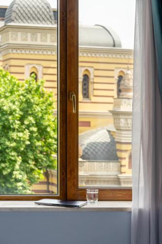 a window with a wine glass sitting on a window sill at Alma Boutique Hotel in Tbilisi City