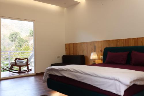 een slaapkamer met een bed en een balkon met een stoel bij FabHotel Prime The Aravali Resort in Rishīkesh