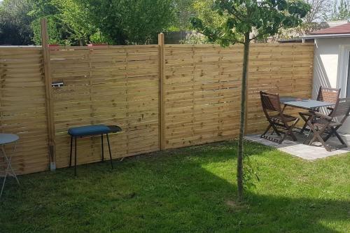 a fence with a table and chairs in a yard at La petite escal' in Dannemois