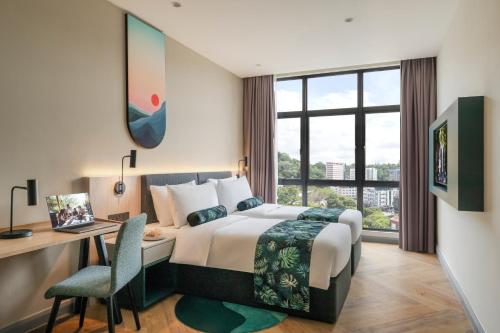 una camera d'albergo con letto, scrivania e finestra di Citadines Waterfront Kota Kinabalu a Kota Kinabalu