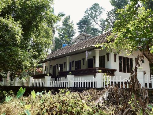 a white house with a white fence and trees at Sanctuary View Homestay Thattekad in Ernakulam