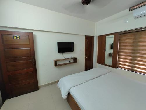 1 dormitorio con 1 cama y TV en la pared en Thampanoor Tourist Home en Thiruvananthapuram