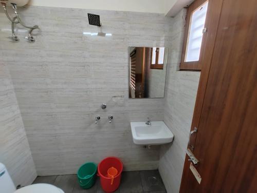 y baño con lavabo, aseo y espejo. en Thampanoor Tourist Home en Thiruvananthapuram
