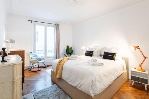 une chambre blanche avec un grand lit et une fenêtre dans l'établissement Stylish 2-bedroom apartment near the famous Moulin Rouge, à Paris