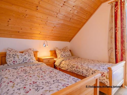 2 bedden in een kleine kamer met houten plafonds bij Chalet in Weinebene with Sauna in Posch Alpe