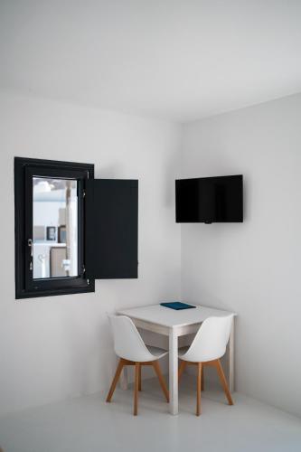a white table with two chairs and a mirror at Caves 1880 in Oia