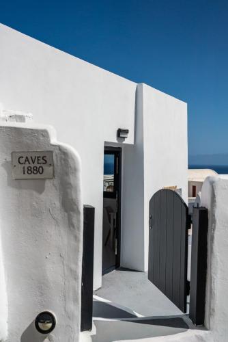 a white building with a door with a sign on it at Caves 1880 in Oia