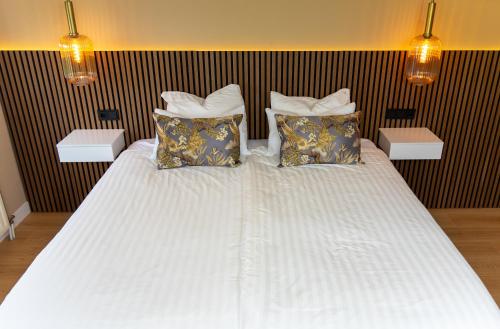 ein großes weißes Bett mit zwei Kissen darauf in der Unterkunft B&B Dijkhuis in Vrouwenpolder