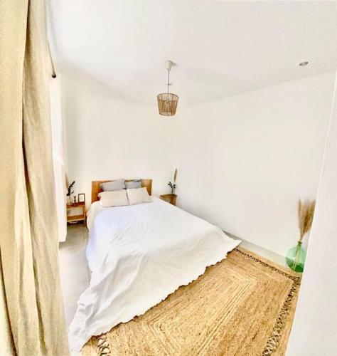 - une chambre blanche avec un lit et un tapis dans l'établissement Maison avec jardin et 3 petits chats , proche du Chateau Lacoste, à Le Puy-Sainte-Réparade