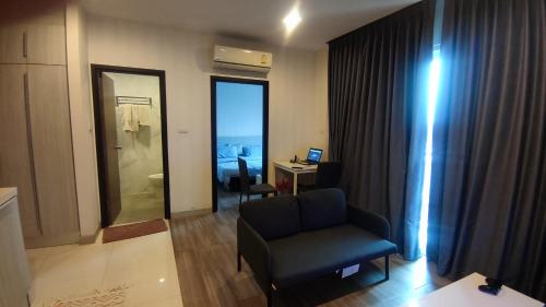 a living room with a chair and a desk with a computer at The Prio Condo in Chiang Mai
