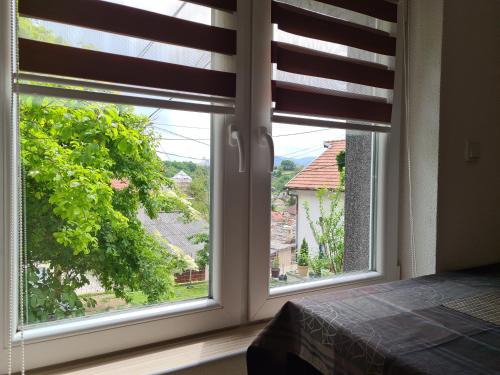 a bedroom with two windows with a view of a house at Leki Apartman in Travnik