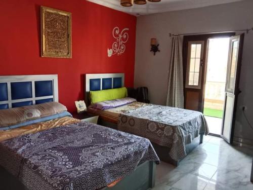 1 dormitorio con 2 camas y pared roja en Marsa Matrouh en Marsa Matruh